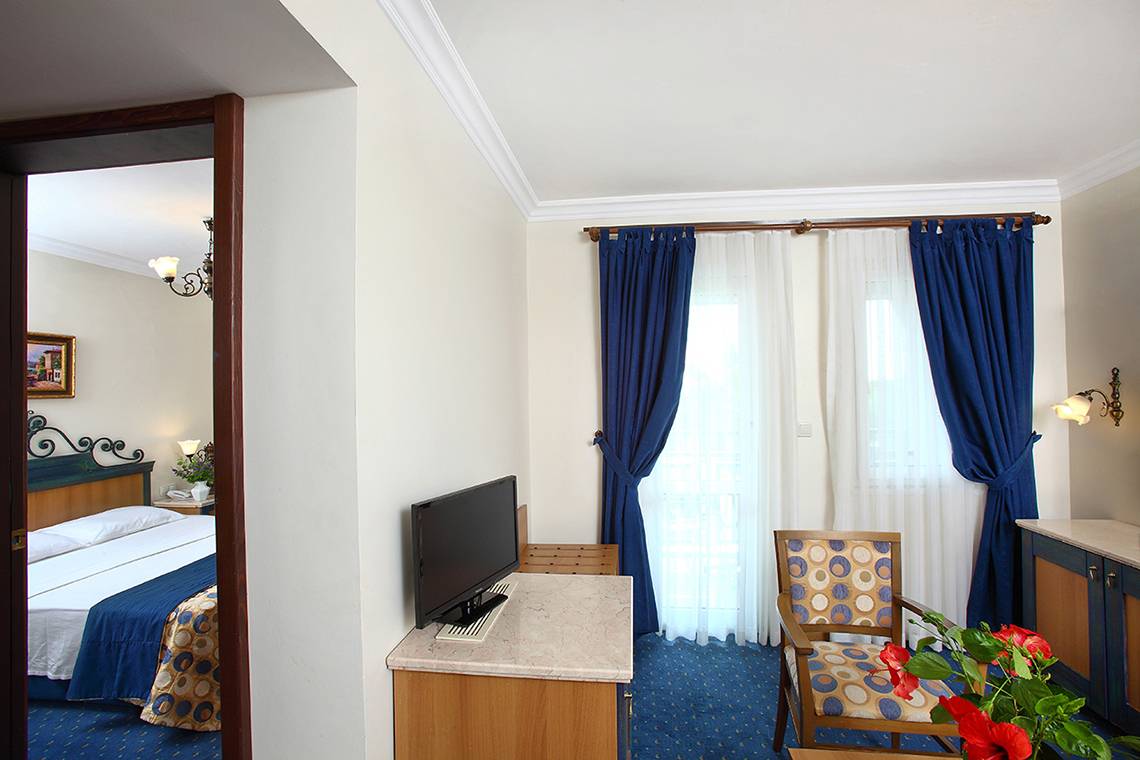 Innenansicht eines Hotelzimmers im Club Yali Hotels & Resort mit Bett, Fernseher, und Dekor.