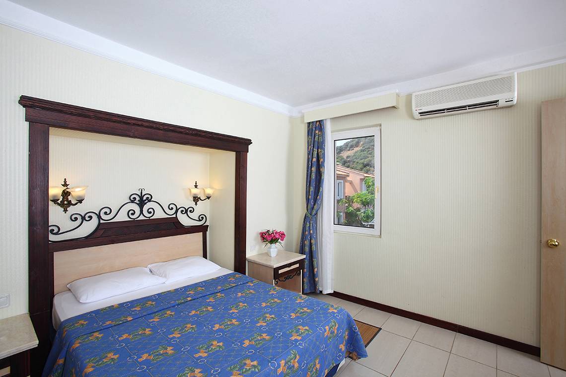 Schlafzimmer im Club Yali Hotels & Resort mit Bett, Nachttisch und Klimaanlage