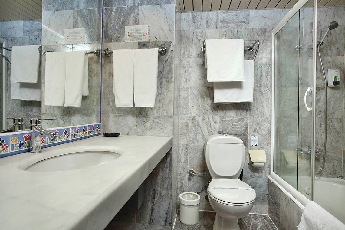 Badezimmer im Club Yali Hotels & Resort mit Marmorfliesen und Glasdusche.