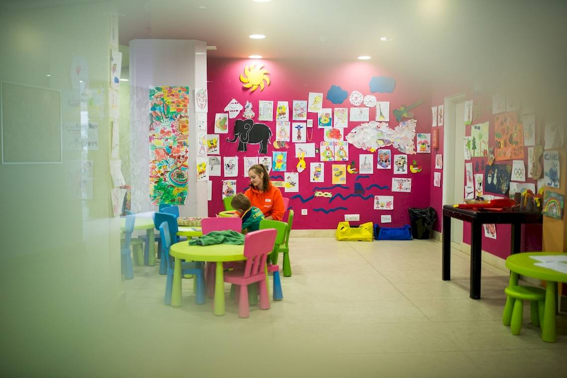 Ein buntes Kinderzimmer im HD Beach Resort mit einer Frau und einem Kind, die an einem Tisch sitzen.