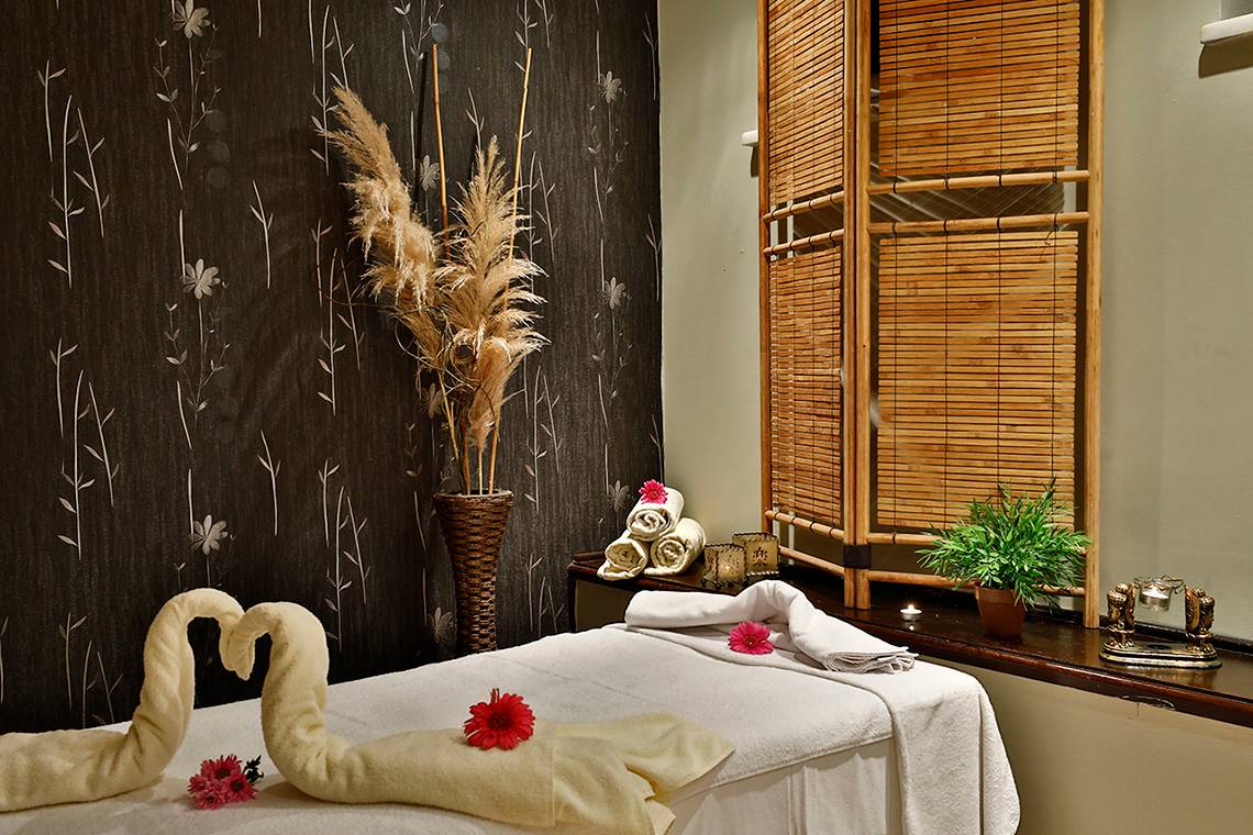 Spa Behandlungsraum im Club Yali Hotels & Resort mit Massagetisch, Handtüchern und Blumendekor.
