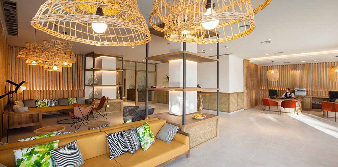 Empfangsbereich des Corallium Dunamar Garden by Lopesan Hotels mit Sofas, Lampen und Schreibtisch.