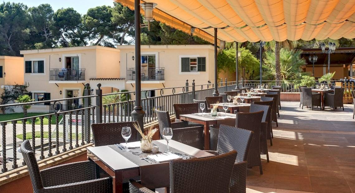 Außenterrasse des Occidental Playa de Palma Hotels mit Tischen und Stühlen unter einem Sonnensegel.