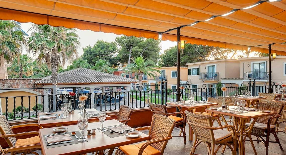 Außenterrasse des Occidental Playa de Palma Hotels mit gedeckten Tischen und Sonnenschirm.