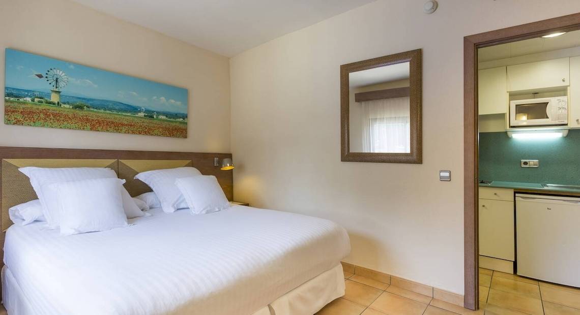 Hotelzimmer im Occidental Playa de Palma mit Bett, Spiegel und Kunstwerk an der Wand.