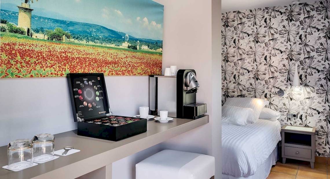 Ein elegantes Hotelzimmer im Occidental Playa de Palma mit einem Schreibtisch, einer Kaffeemaschine und einem Bett.