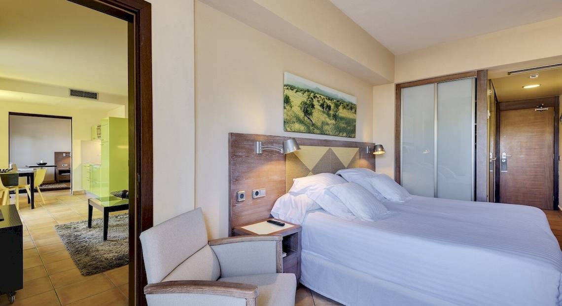 Ein modernes Hotelzimmer im Occidental Playa de Palma mit einem Bett, Nachttisch, Lampe und Panoramafenster.