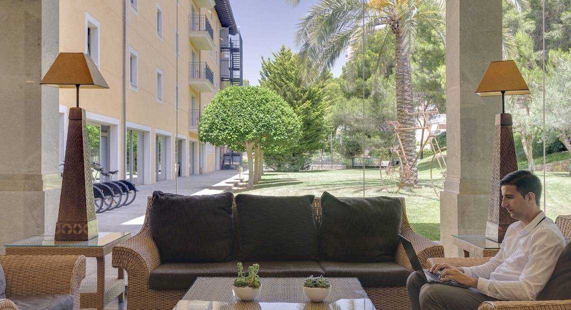 Ein Mann arbeitet im Hotel-Lounge mit Laptop auf einem Tisch vor einem Sofa.