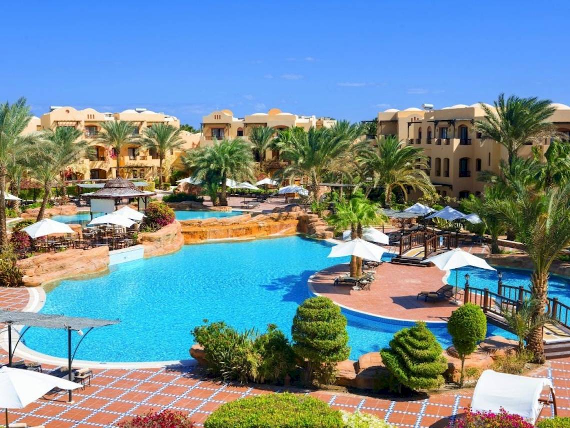 Außenbereich des Pools im Steigenberger Coraya Beach Resort mit Palmen und Liegestühlen.