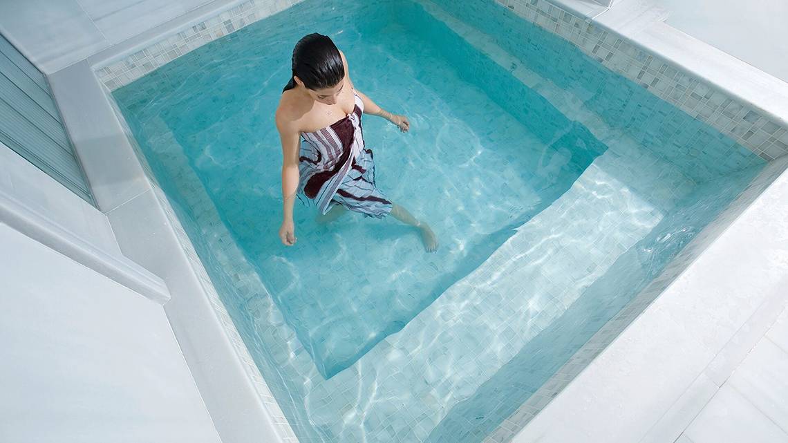 Eine Frau steht im blauen Wasser eines kleinen Beckens im Cornelia Diamond Golf Resort & Spa.