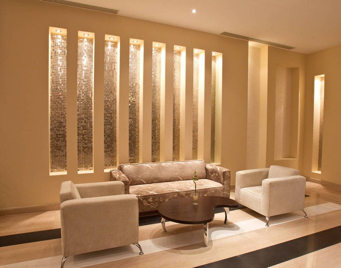 Hotellobby mit gemustertem Sofa und weißen Sesseln neben einer runden Tisch.