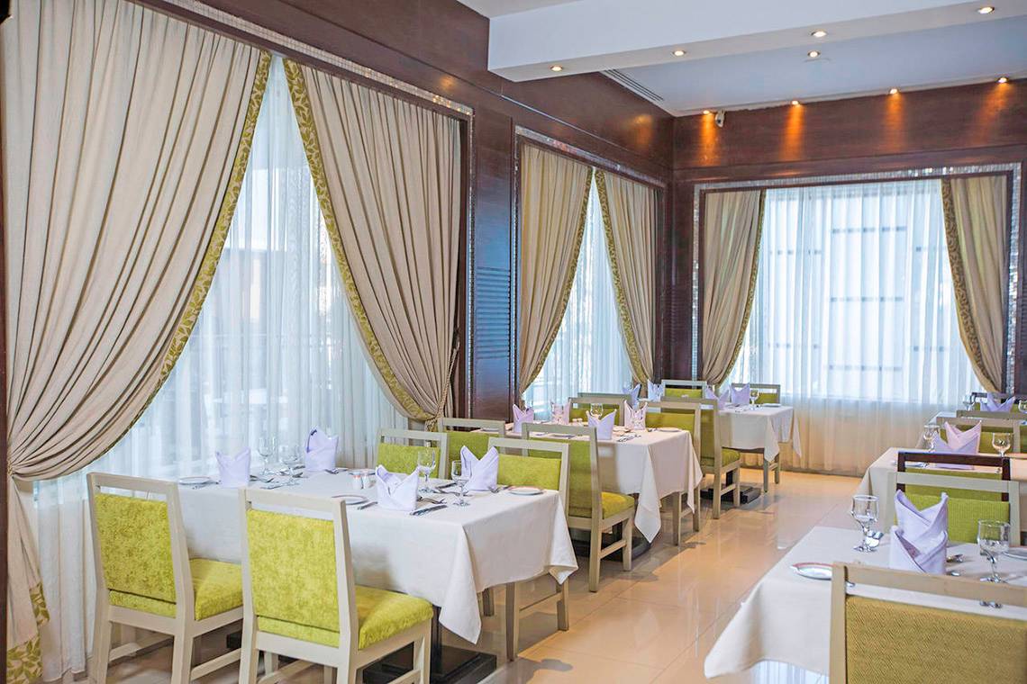 Innenansicht eines Restaurants im Sunrise Crystal Bay Resort mit gedeckten Tischen und Stühlen.