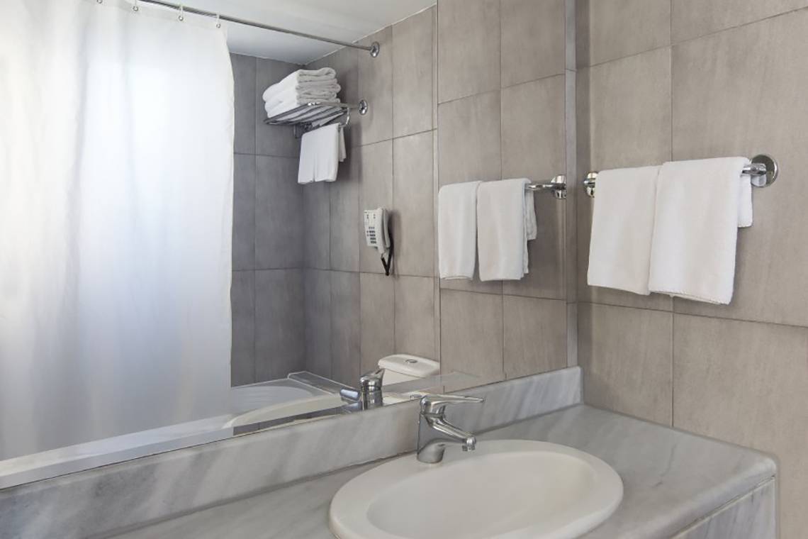 Badezimmer im Atlantica Mikri Poli Rhodes Hotel mit Spiegel, Waschbecken und Handtüchern.