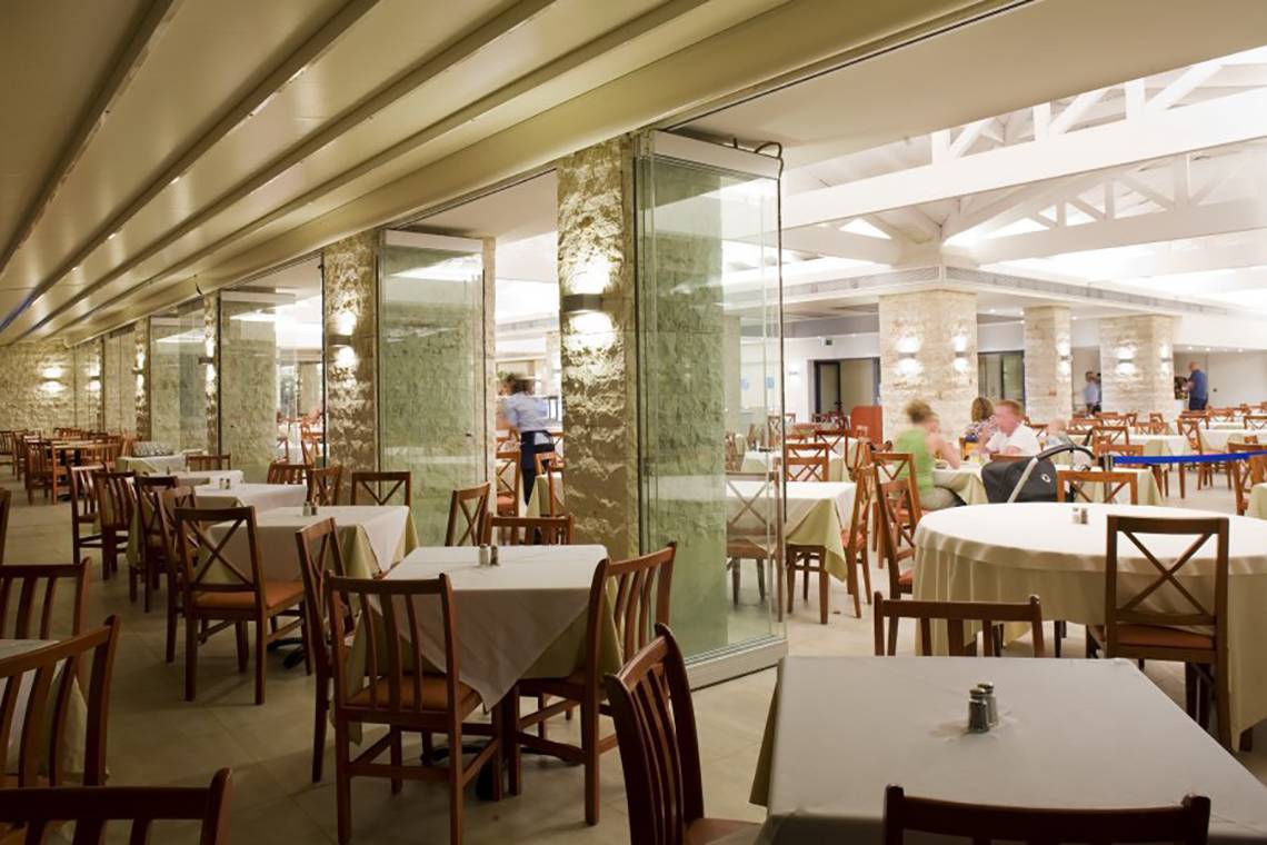 Restaurant des Atlantica Mikri Poli Rhodes Hotels mit vielen Tischen und Stühlen.