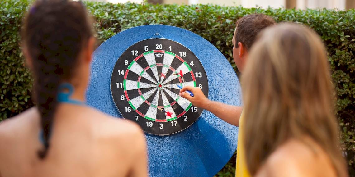 Drei Personen spielen Dart auf einem großen Zielbrett im Freien, Remisens Hotel Epidaurus