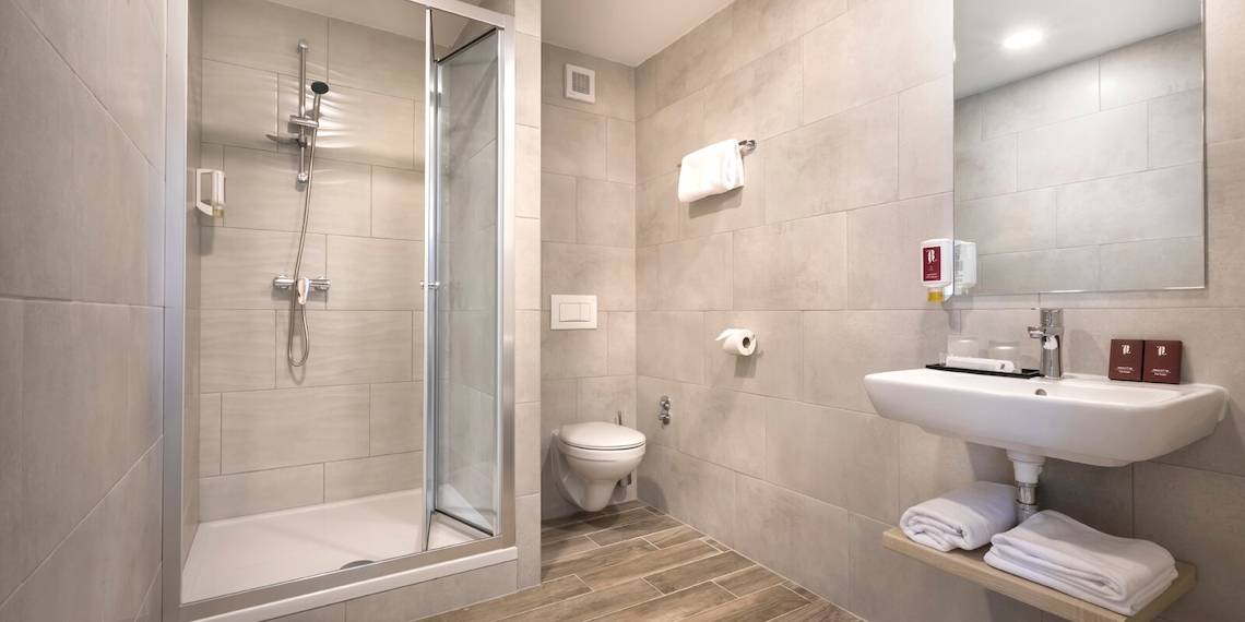 Badezimmer im Remisens Hotel Epidaurus mit Dusche, Toilette und Waschbecken.