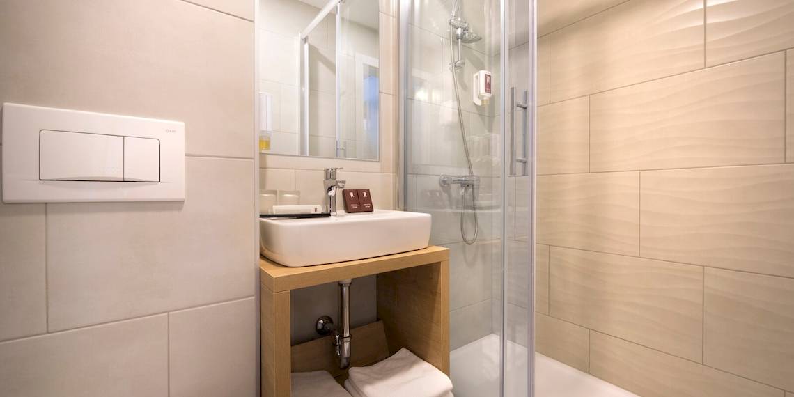 Badezimmer im Remisens Hotel Epidaurus mit weißem Waschbecken und Duschkabine.