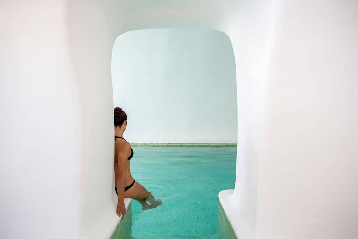 Frau im Pool von Katikies Chromata Santorini, die aus dem Wasser kommt