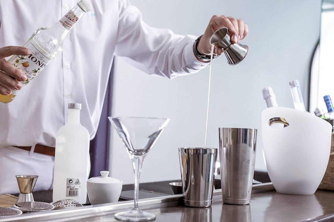 Ein Barkeeper gießt einen Cocktail in ein Glas auf einer Theke.