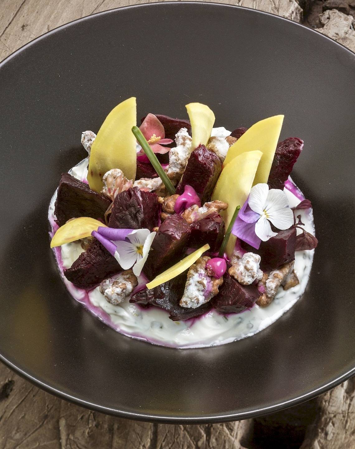 Beetroot-Platte mit verschiedenen Toppings auf einem schwarzen Teller.