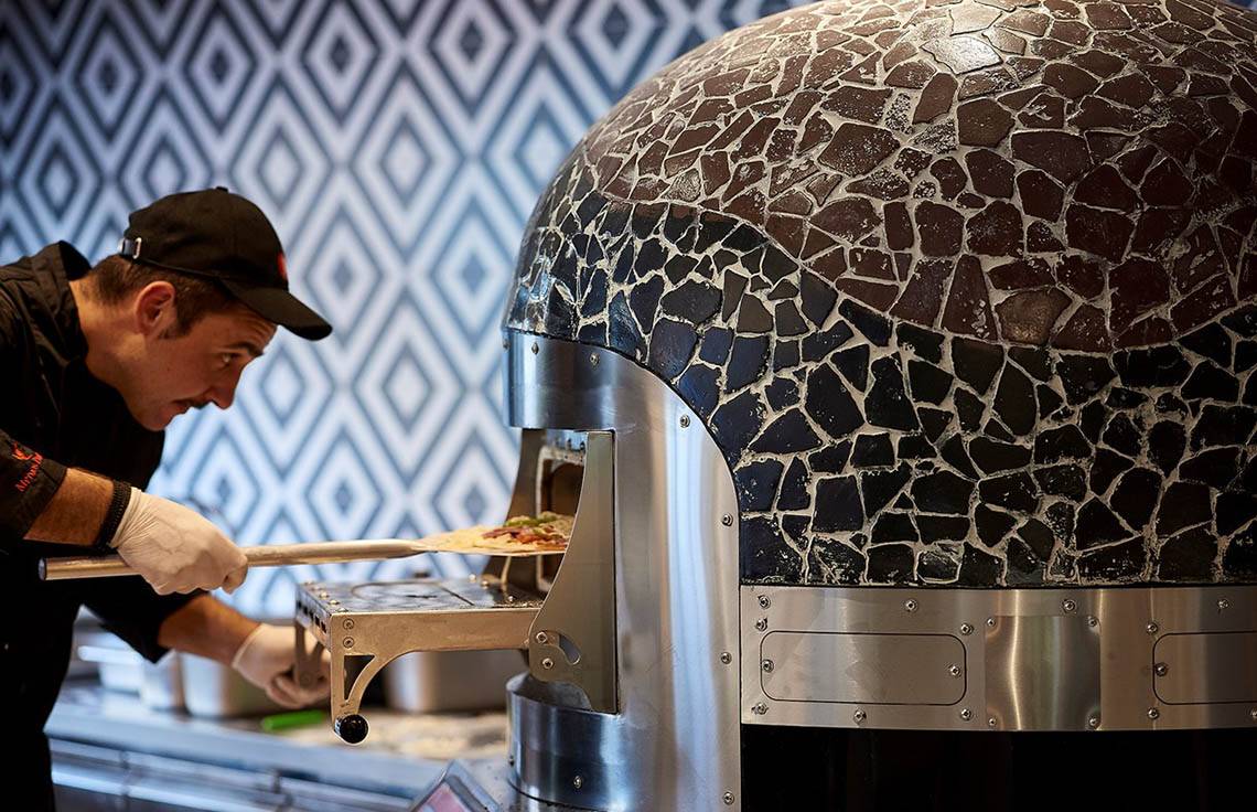 Koch bereitet Pizza im Mythos Palace Resort & Spa im Steinofen zu