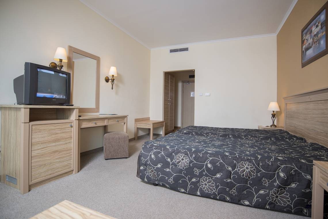 Doppelbettzimmer im DIT Evrika Beach Club Hotel mit Fernseher, Schreibtisch und Spiegel.