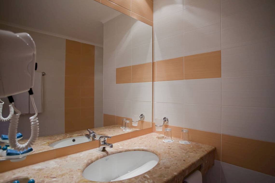 Badezimmer des DIT Evrika Beach Club Hotels mit Doppelwaschbecken und großem Spiegel.