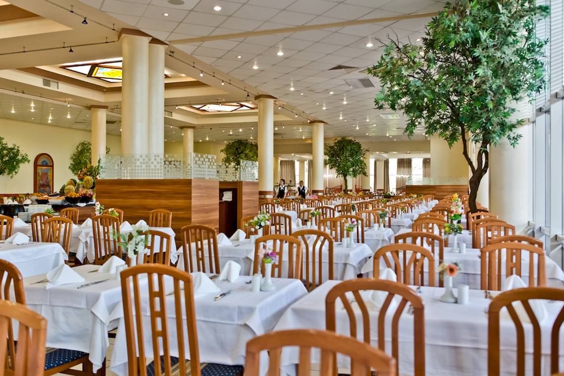 Innenansicht des Restaurants im DIT Evrika Beach Club mit vielen gedeckten Tischen.