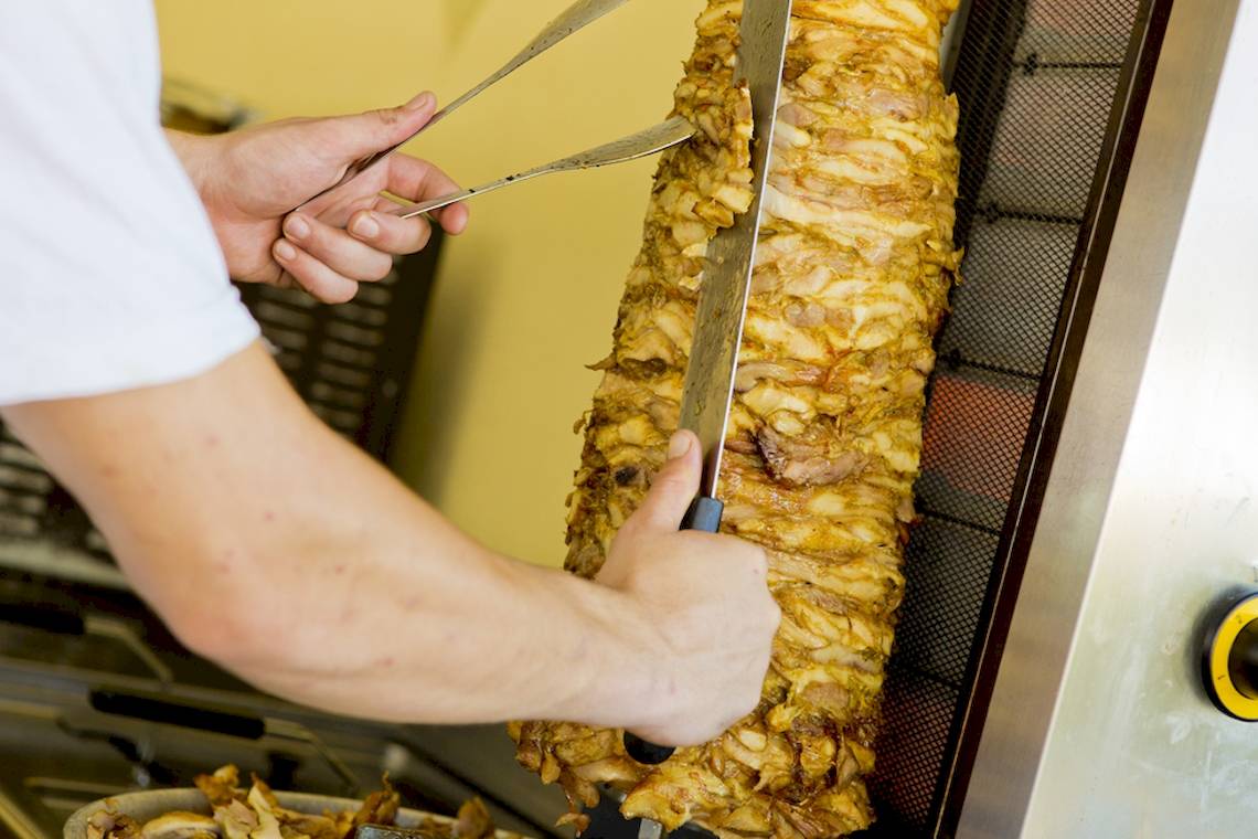Koch im DIT Evrika Beach Club schneidet ein Donerfleisch auf einer Drehspieß