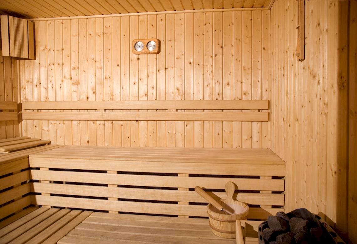 Innenansicht der Sauna des DIT Evrika Beach Clubs mit Holzwänden, Bänken und Thermometer.