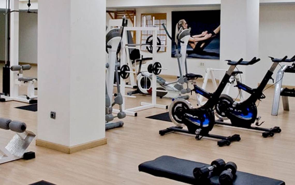 Fitnessstudio im Alexandre Hotel Gala mit verschiedenen Trainingsgeräten und einer Wand mit einem Fitnessposter.
