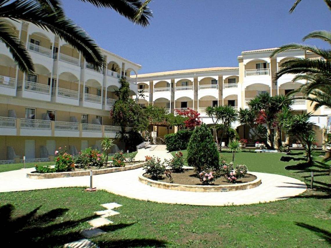 Außenansicht des Poseidon Beach Hotels mit mehreren Gebäuden, Balkonen und umliegenden Gärten.