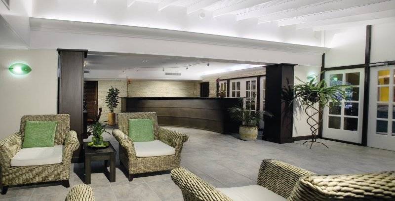 Lobby des Amsterdam Manor Beach Resorts mit zwei Weidenstühlen, einem Tisch und Pflanzen.
