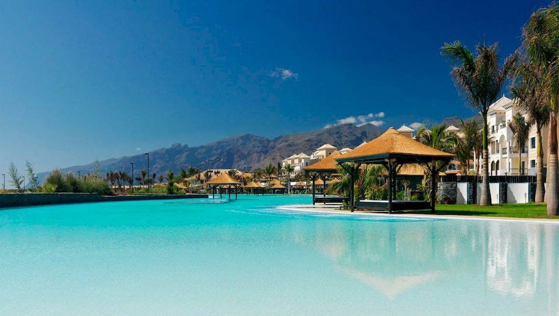 Ein großer Swimmingpool im Freien mit Sonnenschirmen und Blick auf die Berge, das Gran Melia Palacio de Isora Hotel.