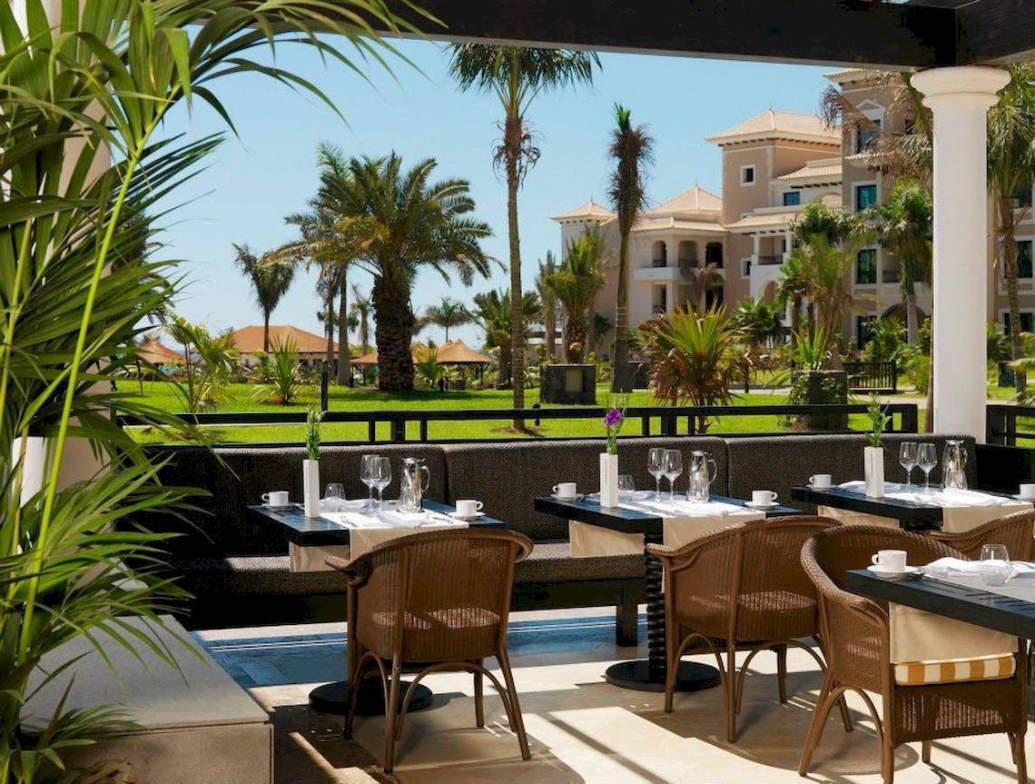 Außenterrasse des Gran Melia Palacio de Isora Hotel mit Blick auf eine gepflegte Landschaft und Gebäude.