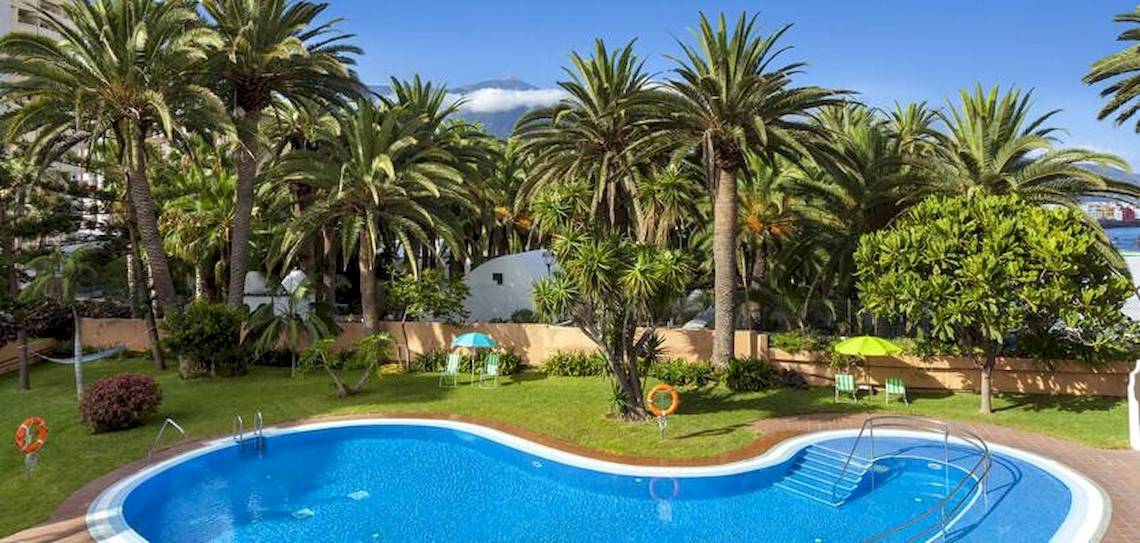 Außenpoolbereich des Gran Melia Palacio de Isora mit Palmen und Rasen