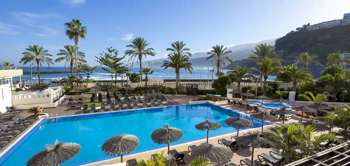 Außenpool im Gran Melia Palacio de Isora Hotel mit Blick auf das Meer und Palmen