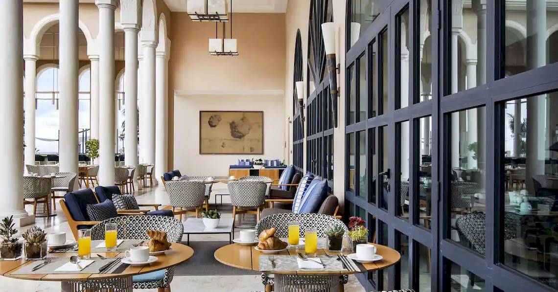 Innenansicht des Restaurants im Gran Melia Palacio de Isora mit blauen Stühlen und Tischen.