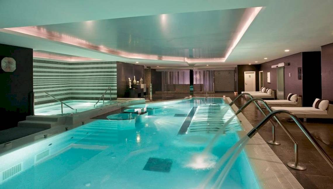 Innenpool des Gran Melia Palacio de Isora Hotels mit blauem Wasser und Lichteffekten.