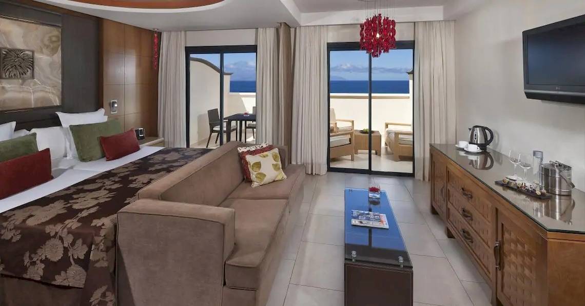 Gran Melia Palacio de Isora Suite Zimmer mit Meerblick, großes Bett, Couch, Tisch, Fernseher und Balkon.