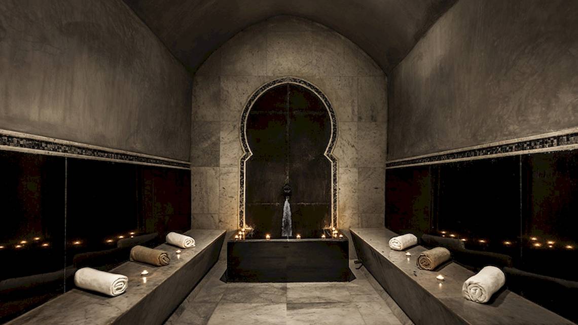Sauna Bereich im Hyatt Place Taghazout Bay Hotel mit drei Ruheräumen, Kerzen und einem Brunnen.