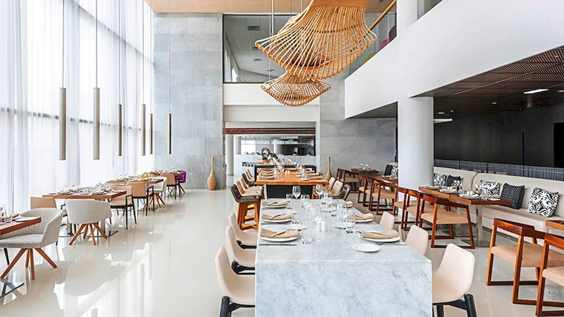 Innenansicht des Restaurants im Hyatt Place Taghazout Bay mit mehreren Tischen, Stühlen und Dekorationen.