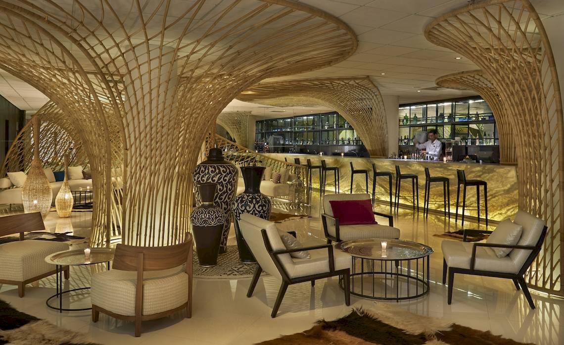 Innenansicht des Hyatt Place Taghazout Bay Hotels mit modernen Möbeln, Vasen und einem Barbereich.