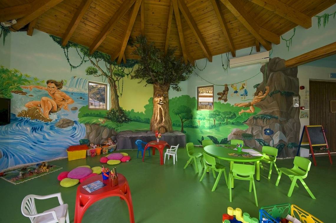 Kinderzimmer im La Marquise Luxury Resort Komplex mit grünen Möbeln und farbigen Wandmalereien.