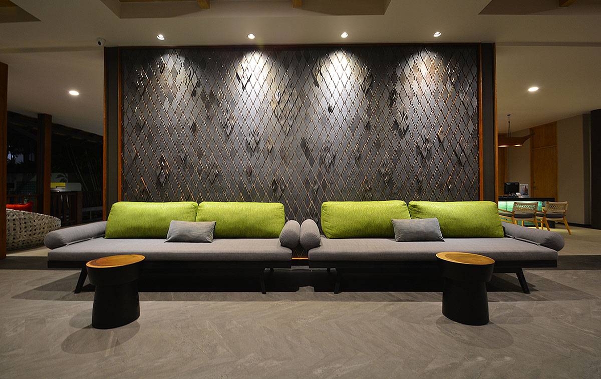 Loungebereich im Andaman Cannacia Resort mit grauen Sofas und grünen Kissen.