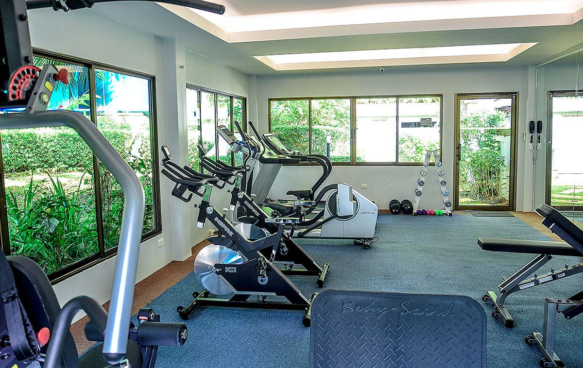 Fitnessraum im Andaman Cannacia Resort mit Cardiogeräten und Fenstern.