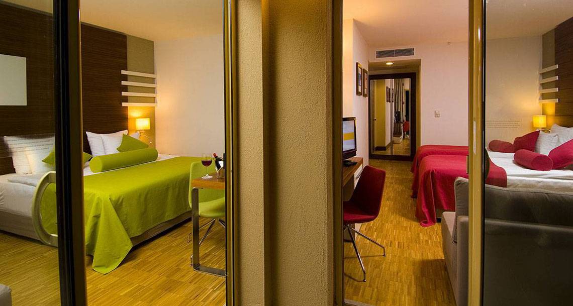 Innenansicht eines Hotelzimmers im Blue Waters Club mit zwei Betten, Schreibtisch und Fernseher.