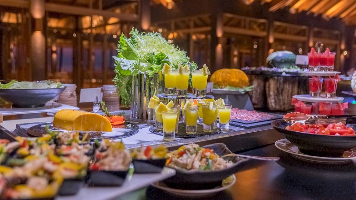 Buffet-Tisch im Innahura Maldives Resort mit verschiedenen Gerichten, Obst und Getränken.
