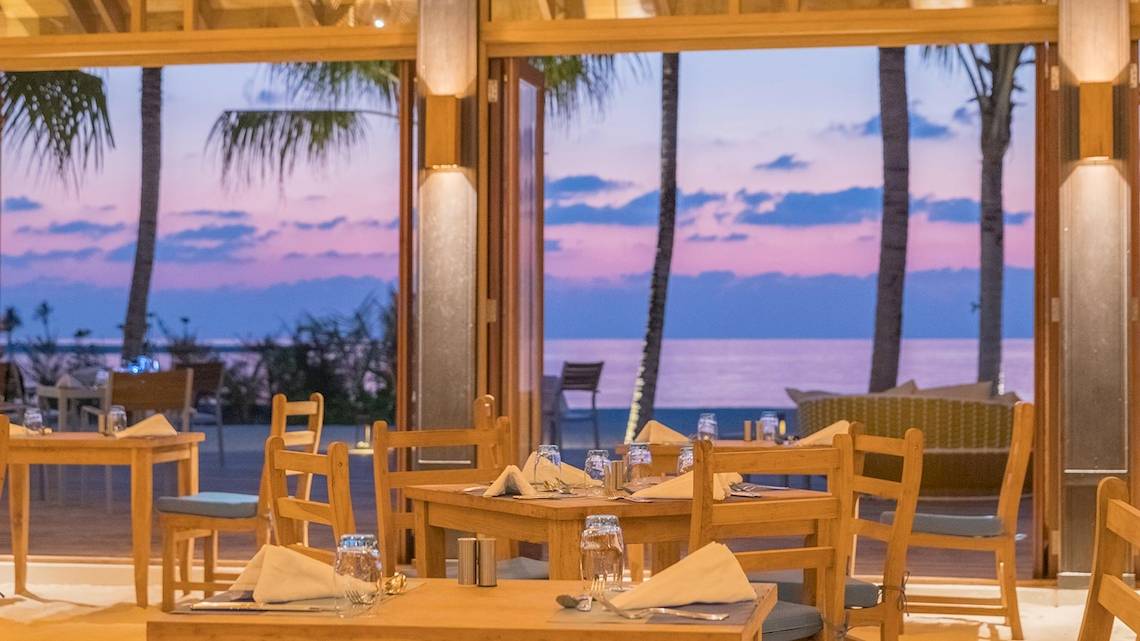 Innenbereich des Innahura Maldives Resorts mit Blick auf das Meer von einem Esstisch aus.