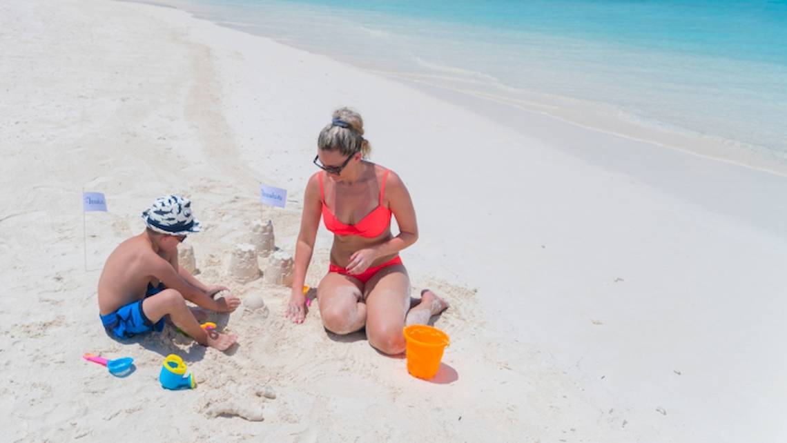 Mutter und Sohn bauen eine Sandburg am Strand des Innahura Maldives Resorts.